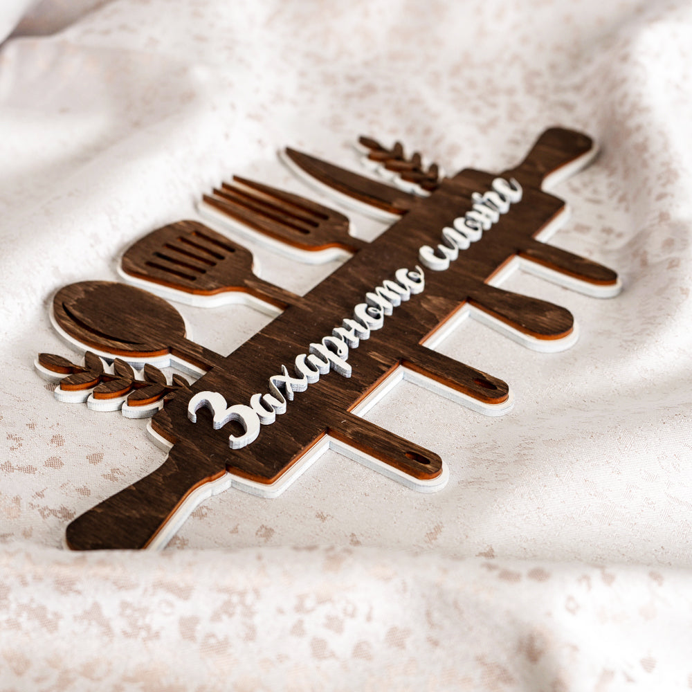 Детайлен фокус на декоративна табелка за кухня точилка с прибори на светъл фон